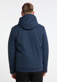 Giacca blu navy con cappuccio, realizzata in tessuto liscio e resistente all'acqua. Caratteristiche includono una vita aderente e dettagli delle cuciture.