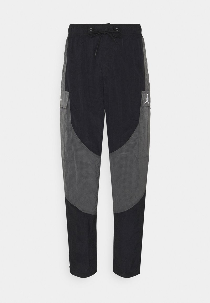 Pantalon cargo bicolore noir et gris avec taille à cordon de serrage et poches à rabat, comportant un petit logo blanc sur la poche droite.