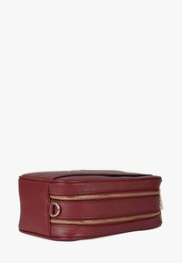 Pochette cosmetica in pelle rossa con finitura strutturata, due chiusure lampo dorate e forma rettangolare con fondo piatto.