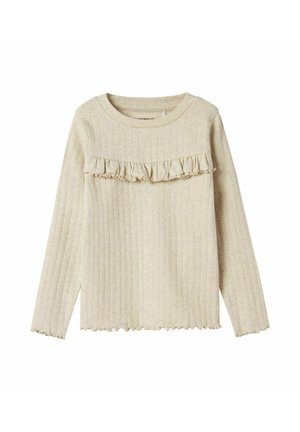 Haut long à manches longues beige clair avec une texture côtelée. Présente une bordure volantée sur la poitrine et un col rond. Les bords sont légèrement effilochés.