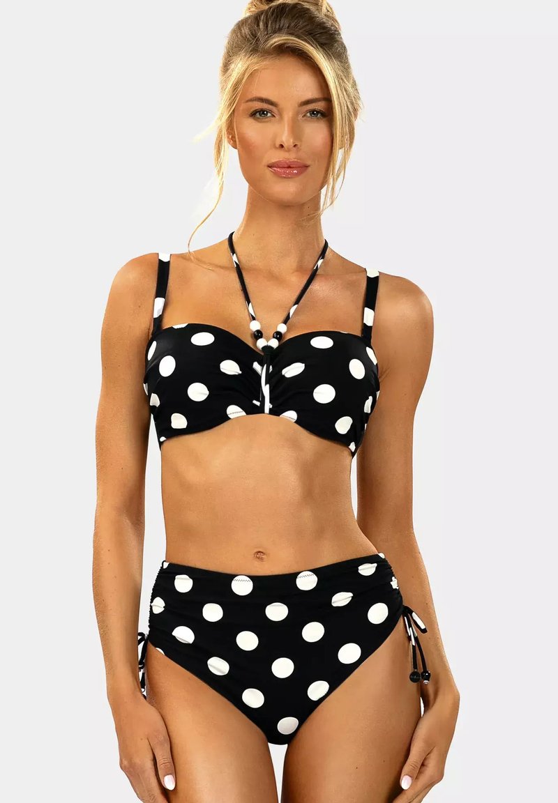 Czarny bikini w białe kropki. Górna część ma skręcony fason i regulowane ramiączka. Dolna część z wysokim stanem i wiązaniami po bokach. Miękka tkanina.