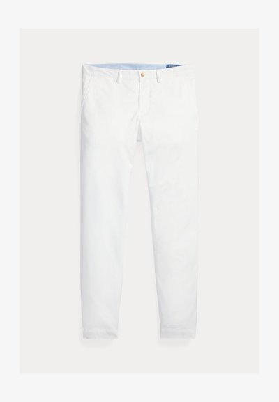 Valkoiset puuvillachino-housut suorella leikkauksella, joissa on vetoketjukiinnitys, nappikiinnitys ja vyölenkit. Tasainen pinta ilman kuvioita.