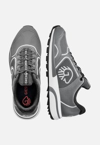 Baskets de sport grises avec un dessus texturé, une silhouette courbée, des accents blancs et un logo rouge contrastant sur la semelle intérieure. Comprend des panneaux en maille et des lacets.
