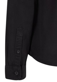 Black cotton shirt close-up, featuring a buttoned cuff with a pointed detail, smooth texture, and contrasting stitching along the seam.