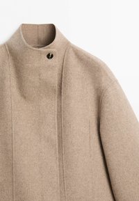 Beige wool coat with a high collar, single visible dark button, clean lines, and minimalist design against a plain white background.