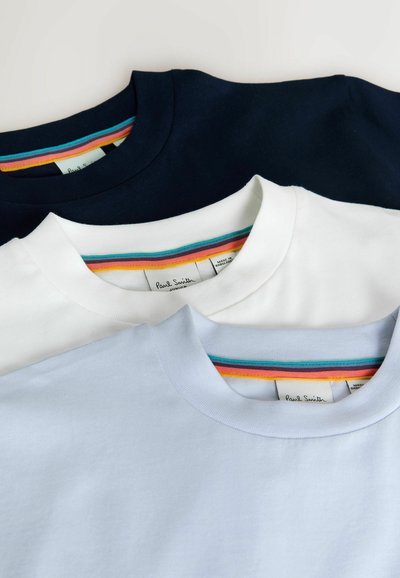 Drei übereinander getragene T-Shirts: eines in Marineblau, eines in Weiß, eines in Hellblau. Jedes hat einen Rundhalsausschnitt und ein gestreiftes Detail im Inneren des Halsausschnitts.