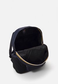 Granatowy plecak z dużym otworem, czarnym wnętrzem, siateczkową boczną kieszenią i kontrastującym żółtym suwakiem. Wykonany z trwałego materiału, wyposażony w regulowane paski.