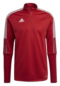 Roter sportlicher Pullover mit hohem Kragen, halbem Reißverschluss, weißem Adidas-Logo und weißen drei Streifen an den Schultern. Glatte Textur.