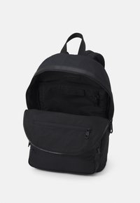 Czarny plecak wykonany z trwałego nylonu, z zamkiem błyskawicznym u góry, przednią kieszenią na zamek oraz regulowanymi paskami. Gładka faktura, minimalistyczny design.