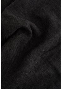 Tumši pelēks audums ar mīkstu, teksturētu virsmu un smalku zivs kaula rakstu, nolikts un nedaudz krunkains, parādot materiāla dziļumu.