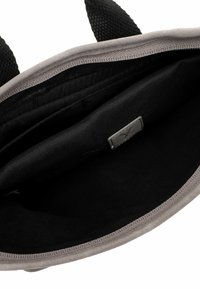 Bolsa tote abierta en gris y negro que muestra un interior espacioso con bolsillo interior y forro de tela negra.