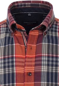 Camicia a quadri con colori arancione, blu navy e bianco. Colletto a bottoni, colletto interno a contrasto e vestibilità casual. Il tessuto sembra testurizzato.