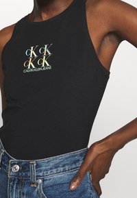 Svart linne med en färgglad "CK"-logotyp i reflekterande finish. Tyget är slätt, med en figurnära design och utan ärmar.