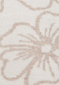 Motif floral beige tissé dans un doux tissu tricoté crème, avec de grands pétales de fleurs et des détails en fil texturé.