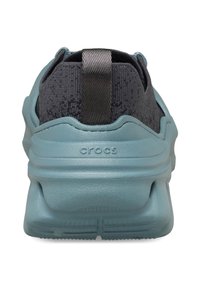 Blauer Gummirücken eines Sneakers mit einem strukturierten dunkelgrauen Obermaterial. Verfügt über eine Zuglasche und ein "CROCS"-Logo an der Ferse. Flache Sohlengestaltung.
