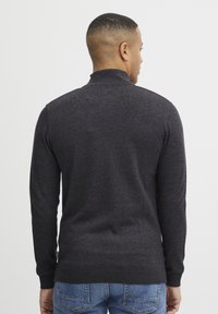 Tumehall sweatshirt kõrge kaelusega, pikkade varrukatega ning soonikkoes mansettide ja alumise äärtega. Kanga pind näib sile, kuid vähese tekstuuriga.