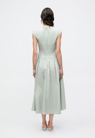 Svetlozelené šaty s krátkymi rukávmi, priliehavým živôtikom a nariaseným pásom, ktoré prechádzajú do sukne dĺžky po kolená, vyrobené z hladkej látky.
