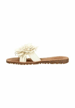 Platte beige slip-on sandaal met een grote stoffen bloem op de band en een geribbelde bruine zool.