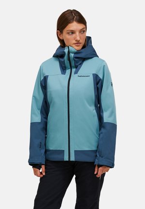 Waterproof jacket in light blue and navy, featuring a zip closure, adjustable hood, and contrasting panels. Designed for outdoor activities.