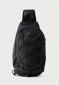 Μαύρο σακίδιο πλάτης με έναν ιμάντα, κατασκευασμένο από ανθεκτικό ύφασμα. Διαθέτει επενδυμένο ιμάντα, τσέπη με φερμουάρ και ελαστικό σχέδιο bungee στο μπροστινό μέρος για αποθήκευση.