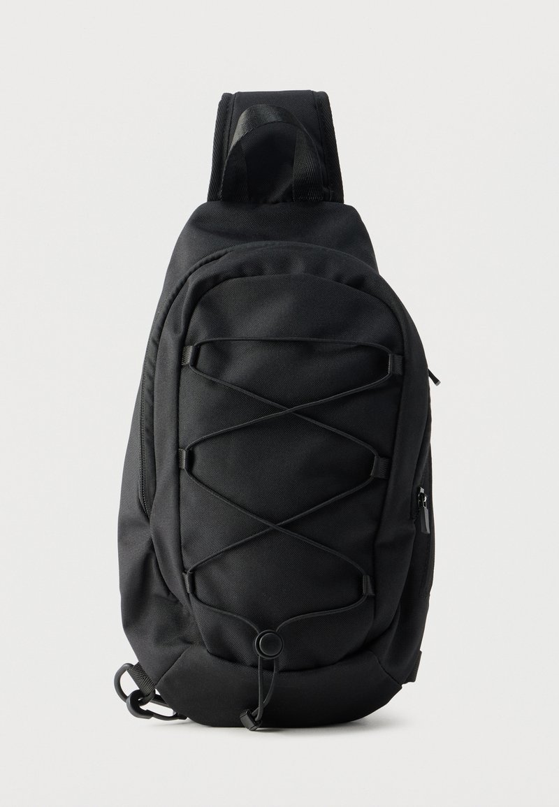 Μαύρο σακίδιο πλάτης με έναν ιμάντα, κατασκευασμένο από ανθεκτικό ύφασμα. Διαθέτει επενδυμένο ιμάντα, τσέπη με φερμουάρ και ελαστικό σχέδιο bungee στο μπροστινό μέρος για αποθήκευση.