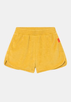 Gule frotté shorts med elastisk talje og sidelommer, med et lille rødt mærke på højre side.