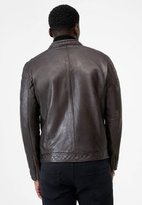 Braune Lederjacke mit einer glatten Textur, ausgestattet mit gesteppten Schulterakzenten, einem Reißverschluss und einem gerippten Kragen.