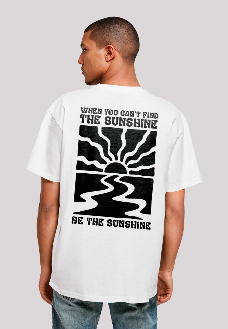 Weißes Baumwoll-T-Shirt mit einem großen schwarzen Grafikdesign auf der Rückseite, das eine Sonne und wellenförmige Linien zeigt, begleitet von Text. Kurzärmlig, lockerer Schnitt.