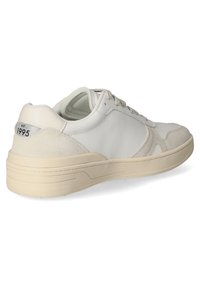 Sneaker bianca con tomaia in pelle liscia e accenti in suede, forma arrotondata, suola beige e una piccola etichetta con "est. 1995" sul tallone.