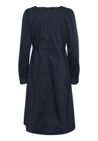 Tumedas sinine kleit, mis on valmistatud kergest kangast, pikad varrukad on nööbitavate mansettidega, kehaosa on liibuv ja seelikuosa on laienev. Selja väljavõttega lukustus.