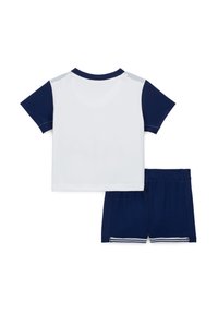 Tweekleurige sportoutfit met een witte T-shirt met korte mouwen en marineblauwe mouwen, gecombineerd met bijpassende marineblauwe shorts met witte streepaccenten.