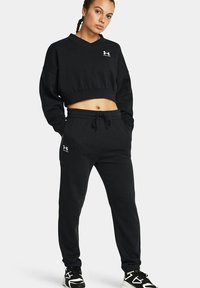 Schwarzes, kurzes Sweatshirt mit V-Ausschnitt und Logodetail, kombiniert mit schwarzen Jogginghosen mit elastischem Bund und seitlichen Taschen.