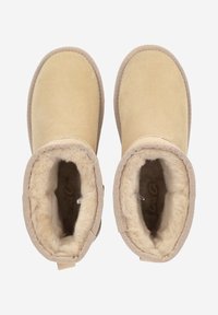 Botines de ante marrón con un suave forro beige y punta redonda. Presentan detalles de costura y una lengüeta en la parte trasera.