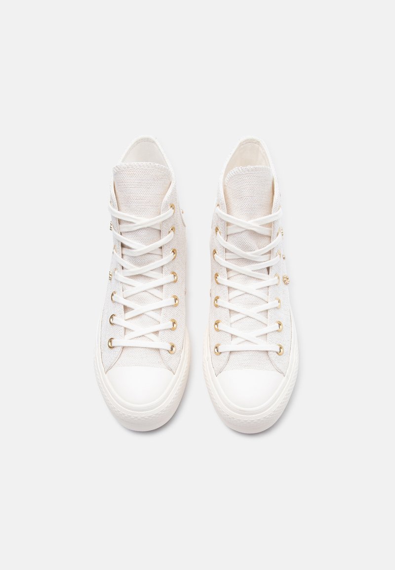 Coppia di sneakers alte in tela bianca con lacci bianchi e occhielli dorati, viste dall'alto su uno sfondo chiaro e semplice.