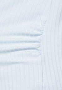 Tecido canelado azul claro com uma textura suave. Apresenta riscas verticais e detalhes franzidos de um lado.