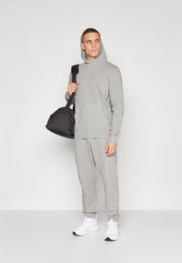 Grå hoodie og sweatpants sæt lavet af blød bomuldsblanding, med en kengurulomme, ribbede cuffedær og en sort duffel bag.