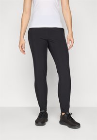 Svarta leggings i stretchmaterial med en smal passform. Matchas med svarta träningsskor och en vit åtsittande topp.