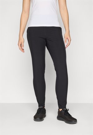  svarte leggings laget av elastisk stoff, med en slim fit-design. Kombinert med svarte treningssko og en hvit tettsittende topp.