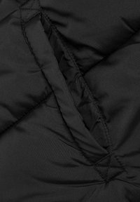 Tissu de doudoune noire avec une texture lisse, présentant un design en losange matelassé et des coutures visibles le long des seams.