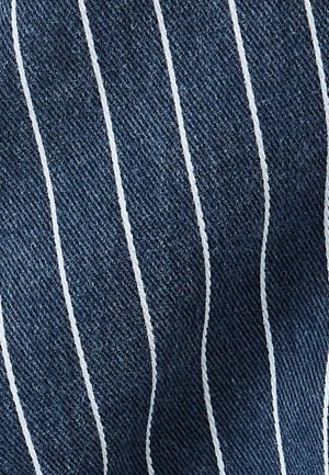 Denim z pionowymi białymi paskami na ciemnoniebieskim tle, z teksturowanym wykończeniem, co zwiększa głębię i wizualne zainteresowanie.