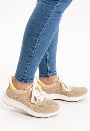 Beige athletic shoes with suede and mesh materials, white soles, and yellow accents. Laces and perforated design for breathability.