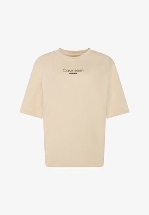 T-shirt beige à manches courtes col rond avec le logo "Calvin Klein JEANS" imprimé en noir sur la poitrine.