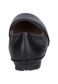 Black leather shoe with a rounded toe, open back, and elastic trim. The sole is textured for grip, with visible stitching along the sides.