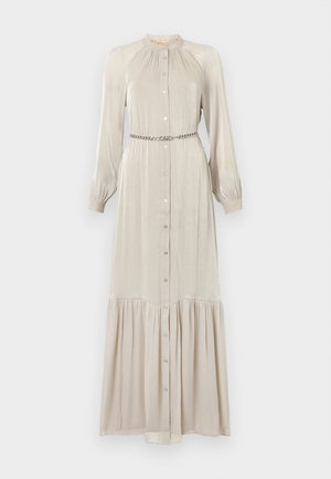 Robe longue beige en tissu brillant, avec un devant à boutons, des manches longues, un col froncé et un ourlet à volants. Inclut une ceinture métallique.