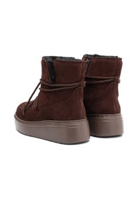 Brūni zamša potītes zābaki ar pūkainu iekšpusi, noapaļotu purngalu un biezu brūnu platformas zoli. Iekļauj auklas un sānu rāvējslēdzēju.