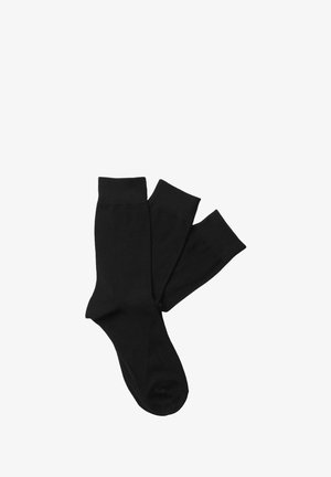 Czarne bawełniane skarpetki o miękkiej fakturze, z prążkowanymi mankietami i klasycznym krojem do kostki. Dwie pary wyeksponowane nakładają się na siebie.
