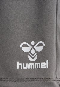 Grått tyg med en slät textur, med en vit logotyp som visar en stiliserad bi och ordet "hummel" nedanför.