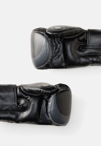 Luvas de boxe pretas com um acabamento em couro suave e detalhes em fibra de carbono cinza. Apresentam costura detalhada e um logotipo circular na manga.