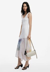 Valge ribakujuline tank-kleit, millel on gradueeritud äär ja pastellvärvides lillemuster. Koos beeži ristiõla kotiga ja mustade kontsakingadega.
