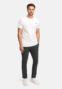 Hvit bomull T-skjorte med en liten svart "JEFF" logo, kombinert med mørkegrå tapered bukser og hvite sneakers. Enkelt design og avslappet passform.
